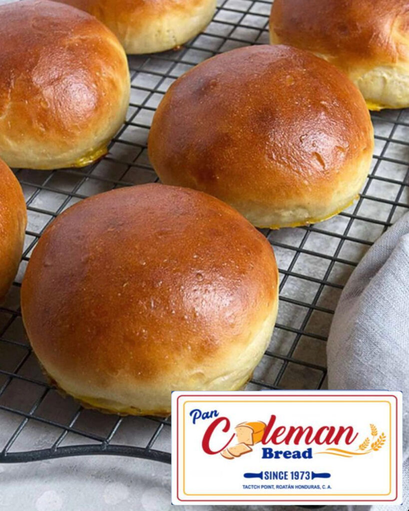 Roatan island-style coconut bread on a cooling rack, "Pan Coleman Bread Since 1973, Tacton Point, Roatan Honduras C.A." logo in bottom right corner of image